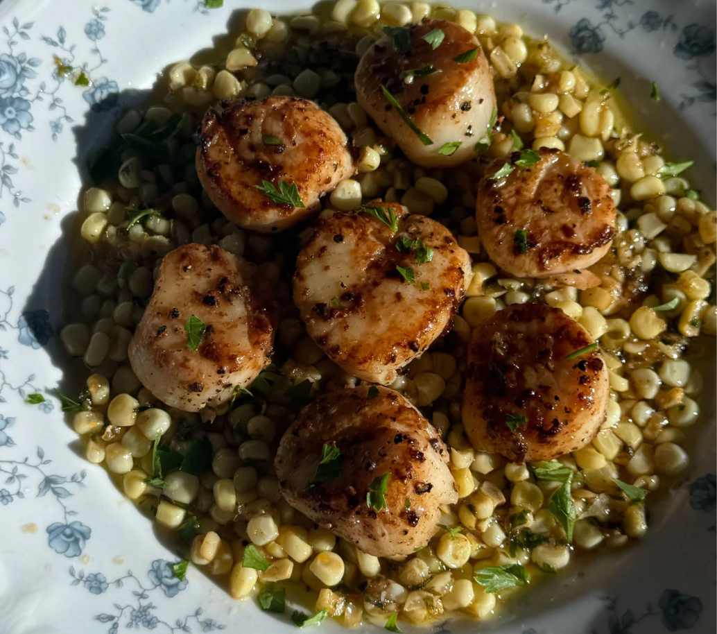 Golden brown pan-seared sea scallops with fresh corn and herb butter.