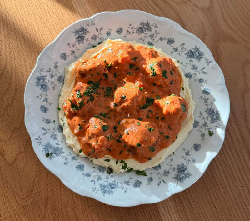 Mini meatballs in creamy vodka sauce served in a Lynnee cream-colored skillet over whipped ricotta.