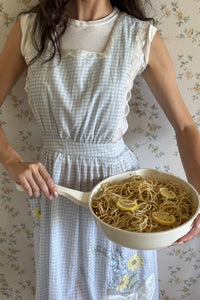 For Love & Lemons x Lynnee Collab, Sydney Carlson wearing Bluebell Gingham Apron, with Cream 11" Fry Pan filled with yummy lemon pasta 